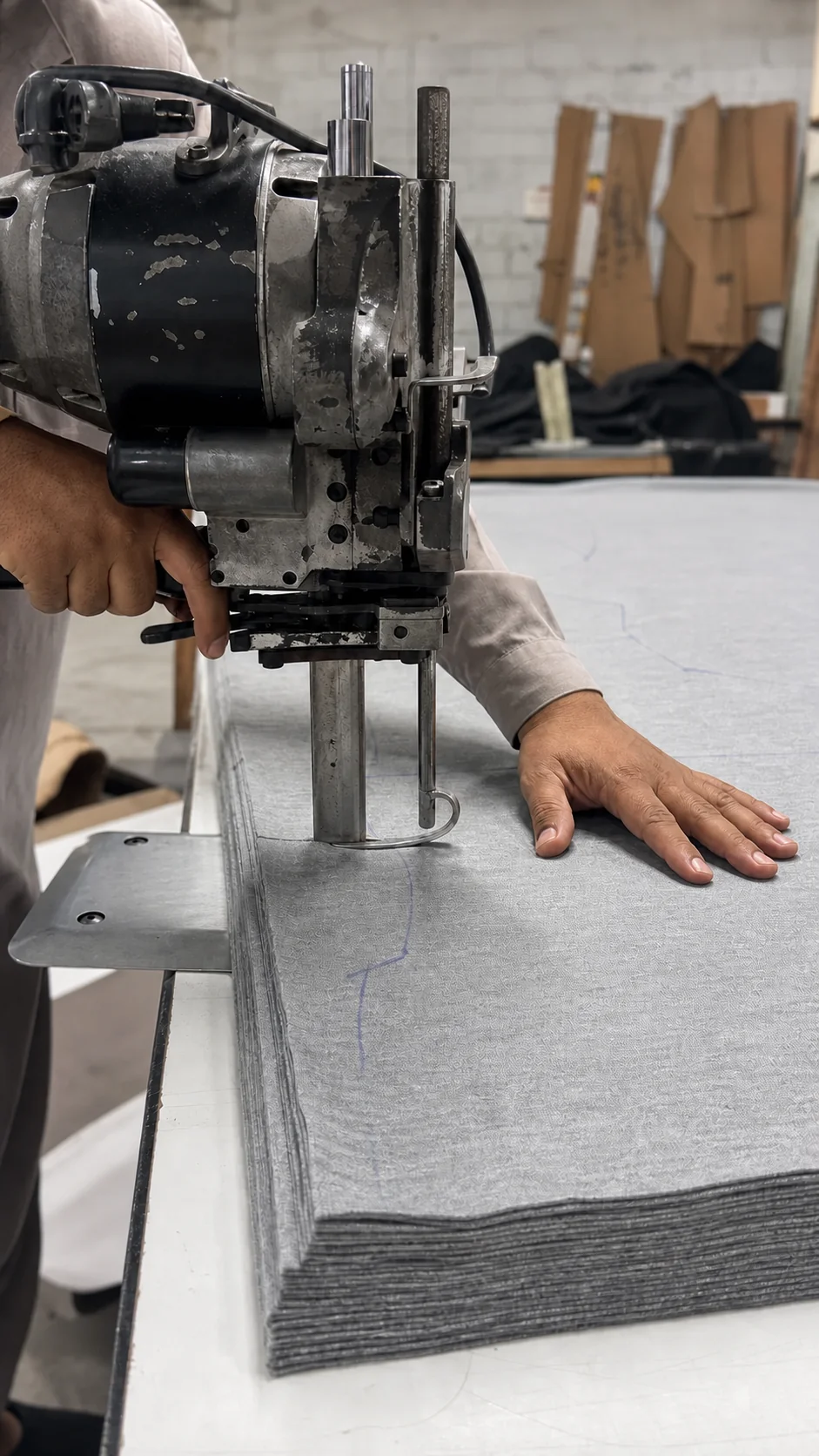 Operator cutting layered fabric with an industrial cutting machine