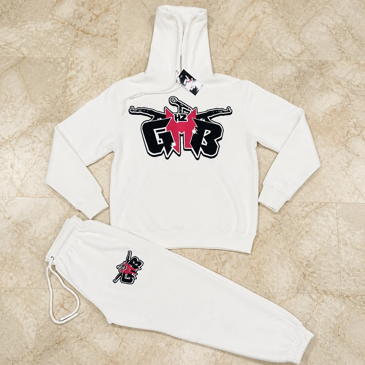White hoodie and jogger set with black and red appliqué graphics and a custom hang tag